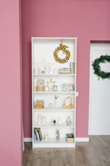 Shelf with Christmas decor in a pink colored living room and hallway in the house