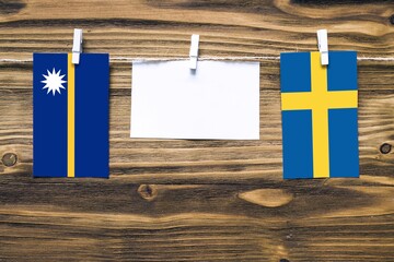 Hanging flags of Nauru and Sweden attached to rope with clothes pins with copy space on white note...