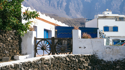 typical white washed holiday rent house with vintage gates made of old wheels in Canary islands near ocean