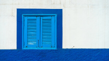 Mediterranean white washed house with blue wooden window shutters