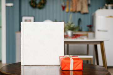 White wedding photo book with a leather cover with lace and a red Christmas gift box on the table