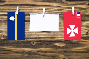 Hanging flags of Nauru and Wallis And Futuna attached to rope with clothes pins with copy space on...