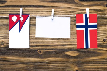 Hanging flags of Nepal and Norway attached to rope with clothes pins with copy space on white note...