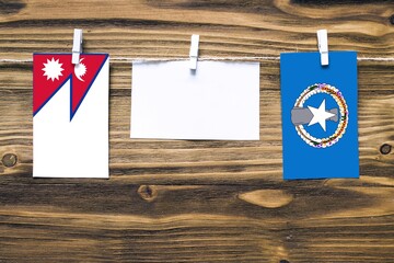 Hanging flags of Nepal and Northern Mariana Islands attached to rope with clothes pins with copy...