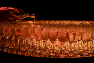 The waiter in pours the champagne into the glasses from the bottle in the restaurant. Catering service, banquet. 