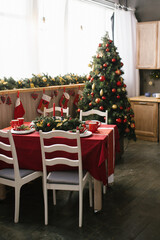 Traditional dining room decorated for Christmas and New Year, spruce with red and gold Christmas toys, table and chairs. Dinner table