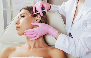 botulinum toxin injections in forehead. Anti aging procedure after 30 years, cosmetologist making...