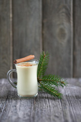 Homemade eggnog with cinnamon for Christmas and winter holidays on wooden table.