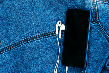 phone with white headphones on a denim background
