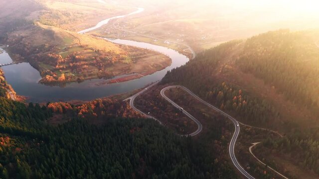 Flight over the autumn mountains with mountain road serpentine, river and forest. Ukraine, Carpathian mountains