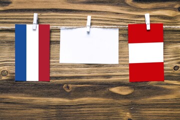 Hanging flags of Netherlands and Peru attached to rope with clothes pins with copy space on white note paper on wooden background.Diplomatic relations between countries.