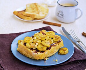 Breakfast, french toasts with banana, walnuts and honey on a gray plate on a light concrete...