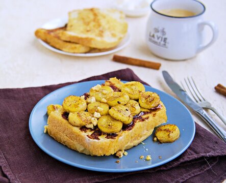 Breakfast, french toasts with banana, walnuts and honey on a gray plate on a light concrete background. French cuisine