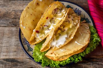Mexican potato fried tacos with cheese and sour cream on wooden background
