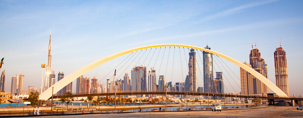 colorful sunset over Dubai Downtown skyscrapers and the newly built Tolerance bridge as viewed from the Dubai water canal