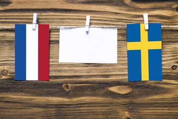 Hanging flags of Netherlands and Sweden attached to rope with clothes pins with copy space on white...
