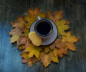 cup of coffee on a wooden table on a background of autumn leaves