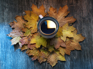 cup of coffee on a wooden table on a background of autumn leaves