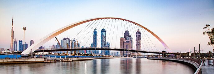 colorful sunset over Dubai Downtown skyscrapers and the newly built Tolerance bridge as viewed from the Dubai water canal