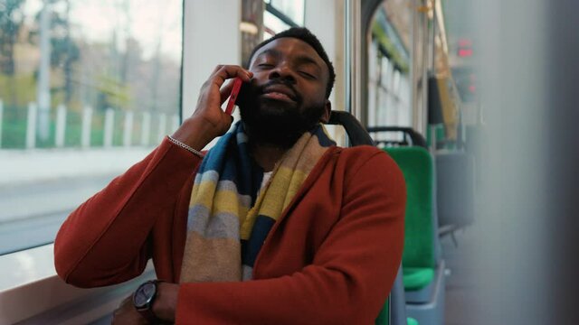 Tired african american man use speak on smartphone sitting in tram traffic typing handsome passangers stylish transportation using way internet online texting guy slow motion