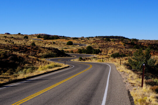 A two lane road is winding through the desert terrain of the southwest USA