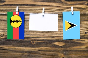 Hanging flags of New Caledonia and Saint Lucia attached to rope with clothes pins with copy space...