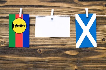 Hanging flags of New Caledonia and Scotland attached to rope with clothes pins with copy space on...