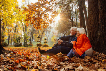 Close up portrait of a happy old woman and man in a park in autumn foliage.