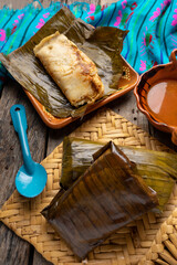 Mexican tamales wrapped in banana leaves also called "oaxaqueños" on wooden background