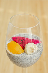 Glass of chia healthy food coconut pudding with banana, mango and dragon fruit on the bamboo background. Healthy concept