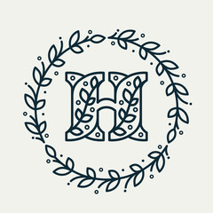 H letter logo consisting of floral pattern in a circle laurel wreath. Linear heraldic vector font.