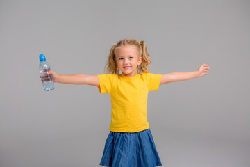 little girl smiling holding bottle of water,Healthy and hydrated. Girl cares about health and water balance.
