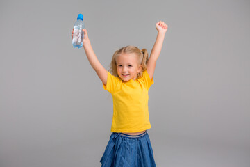 little girl smiling holding bottle of water,Healthy and hydrated. Girl cares about health and water balance.
