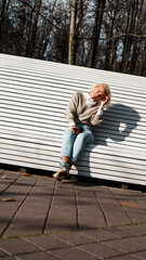 Pretty woman in sunglasses on bench at autumn park alone, lifestyle people concept