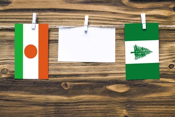 Hanging flags of Niger and Norfolk Island attached to rope with clothes pins with copy space on...