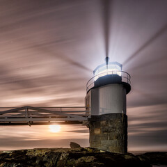 Lighthouse at night with the moon rising behind it