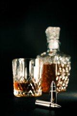Obraz na płótnie Canvas Pistolenkugeln und Whiskeyglas vor schwarzem Hintergrund