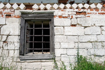 Fototapeta na wymiar a fragment of wrought iron grating on a window on an old white brick wall