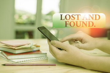 Writing note showing Lost And Found. Business concept for a place where lost items are stored until they reclaimed woman using smartphone and technological devices inside the home