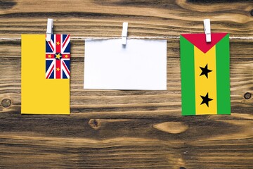 Hanging flags of Niue and Sao Tome And Principe attached to rope with clothes pins with copy space...