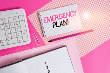 Writing note showing Emergency Plan. Business concept for actions developed to mitigate damage of potential events Writing equipments and computer stuffs placed above colored plain table