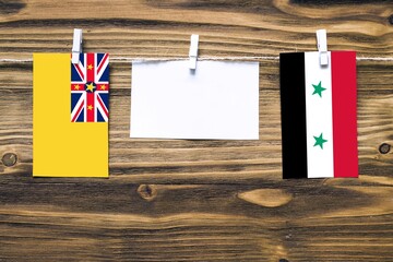 Hanging flags of Niue and Syria attached to rope with clothes pins with copy space on white note...