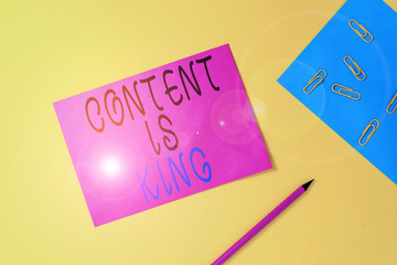 Writing note showing Content Is King. Business concept for marketing focused growing visibility non paid search results Blank paper sheets message pencil clips binder plain colored background