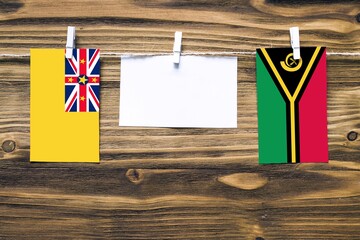 Hanging flags of Niue and Vanuatu attached to rope with clothes pins with copy space on white note...