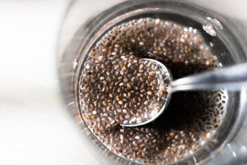 Top view on glass containing chia seeds gel with partially submerged spoon.