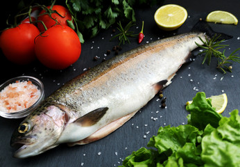 Fresh trout with vegetables on a dark table