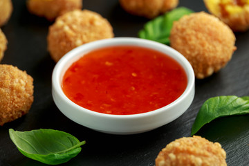 Fried Rice Balls with sweet hot sauce and wooden chopstick on rustic stone board