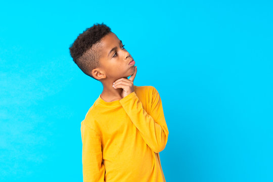 African American boy over isolated blue background having doubts and with confuse face expression