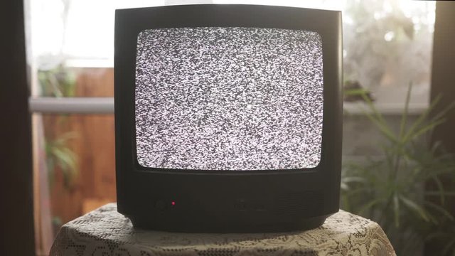 Old analog tv set in vintage interior. The screen shows noise. No signal.
