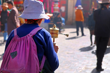 People dressed in traditional clothes walking and praying on the old streets of Lhasa, Tibet.